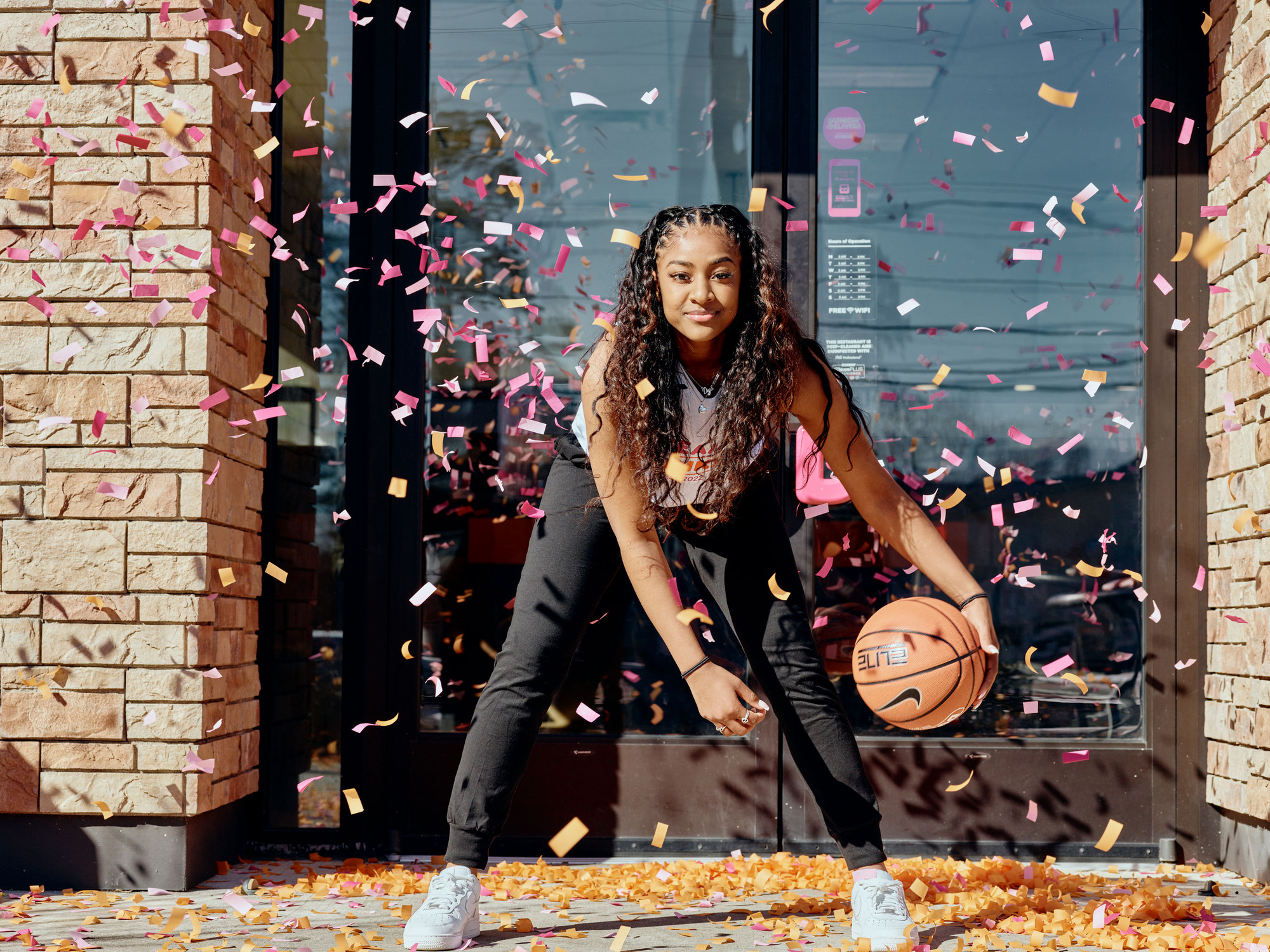  Deja Kelly posing with a basketball surrounded by Dunkin’ confetti